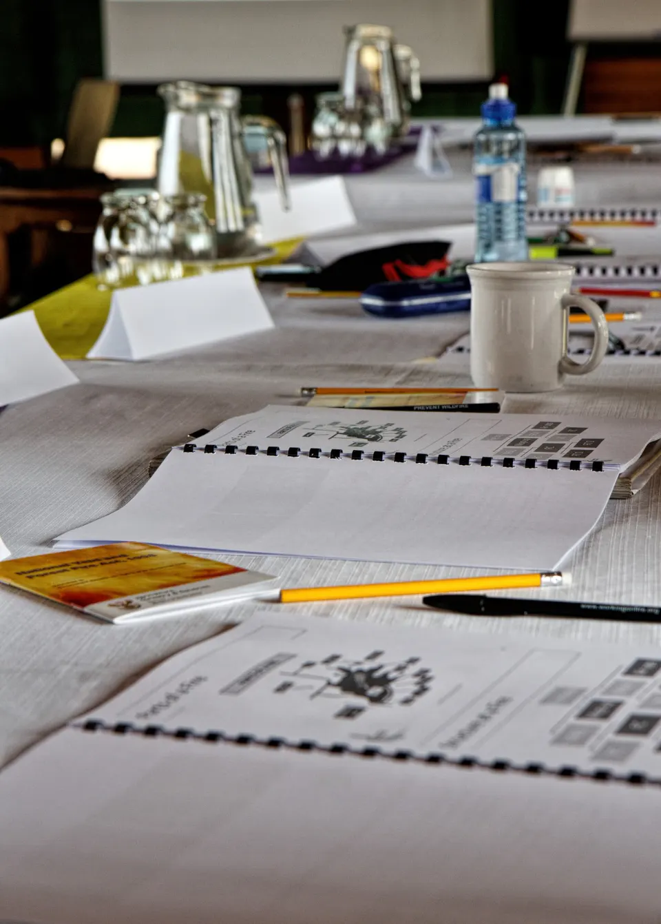 Conference papers, notepads and pens laid out on a table.